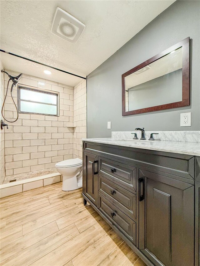 8648 78th Pl, Seminole, FL 33777 - full bathroom featuring a tile shower, toilet, wood finished floors, a textured ceiling, and vanity