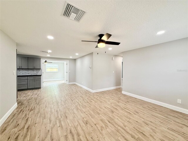8648 78th Pl, Seminole, FL 33777 - unfurnished living room featuring a ceiling fan, light wood finished floors, recessed lighting, baseboards, and a textured ceiling