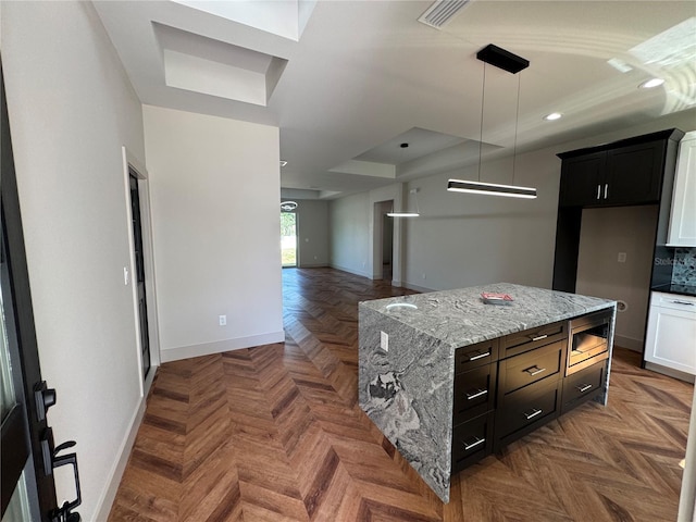 7208 N Glen Ave, Tampa, FL 33614 - kitchen with a tray ceiling, stainless steel microwave, baseboards, light stone countertops, and visible vents