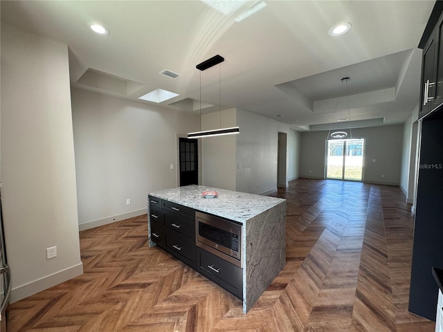 7208 N Glen Ave, Tampa, FL 33614 - kitchen with a raised ceiling, visible vents, dark cabinetry, stainless steel microwave, and baseboards