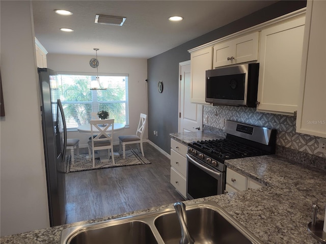 kitchen featuring white cabinets, dark wood-style flooring, appliances with stainless steel finishes, and tasteful backsplash
