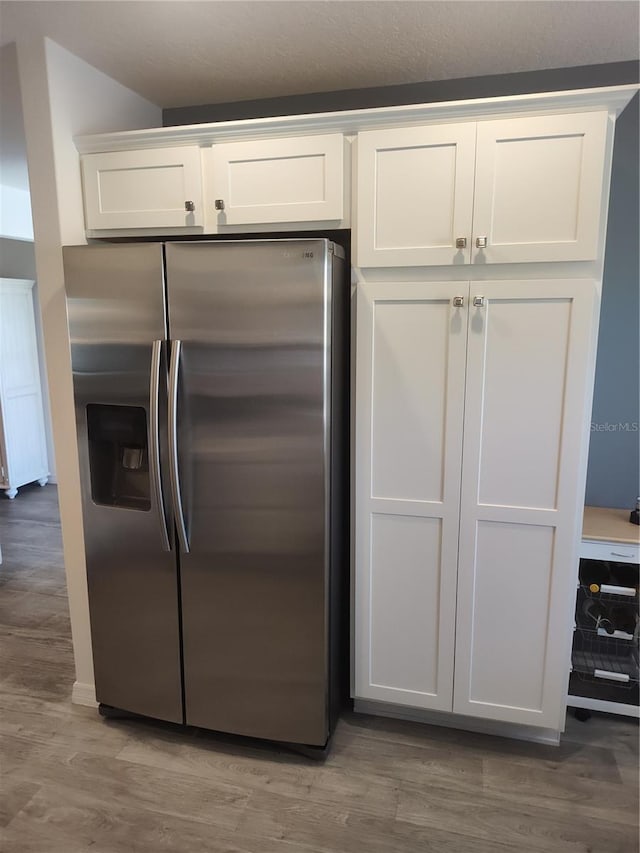 kitchen with stainless steel fridge, light wood-style floors, and white cabinetry