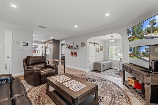 living room featuring arched walkways, light wood-type flooring, visible vents, and baseboards