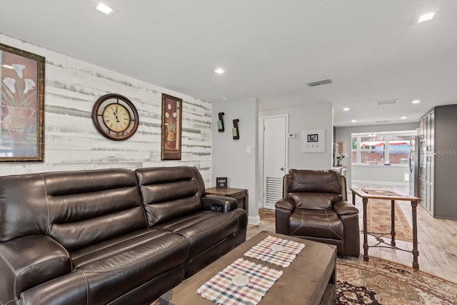 living room with recessed lighting, wood finished floors, visible vents, an accent wall, and baseboards