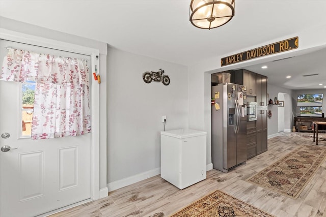 foyer with light wood-style floors and baseboards