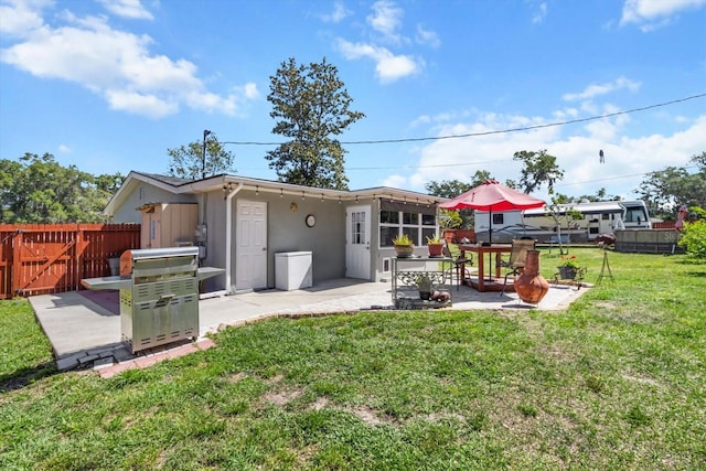 rear view of property with stucco siding, fence, a yard, and a patio