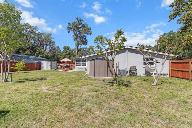 view of yard with fence, an outbuilding, and a shed