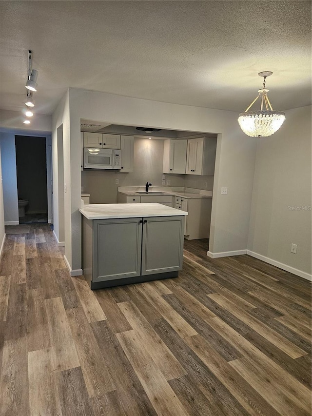 414 Danube Ave, Tampa, FL 33606 - kitchen featuring a sink, white microwave, dark wood-type flooring, gray cabinetry, and baseboards