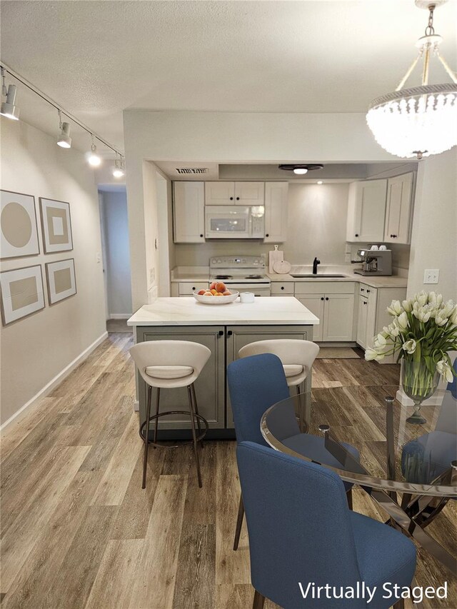 414 Danube Ave, Tampa, FL 33606 - kitchen featuring white appliances, a sink, rail lighting, light countertops, and light wood-type flooring