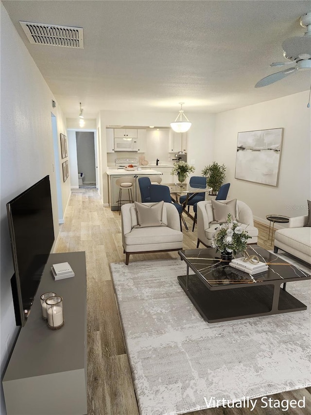 414 Danube Ave, Tampa, FL 33606 - living room with baseboards, light wood-style flooring, visible vents, and a ceiling fan