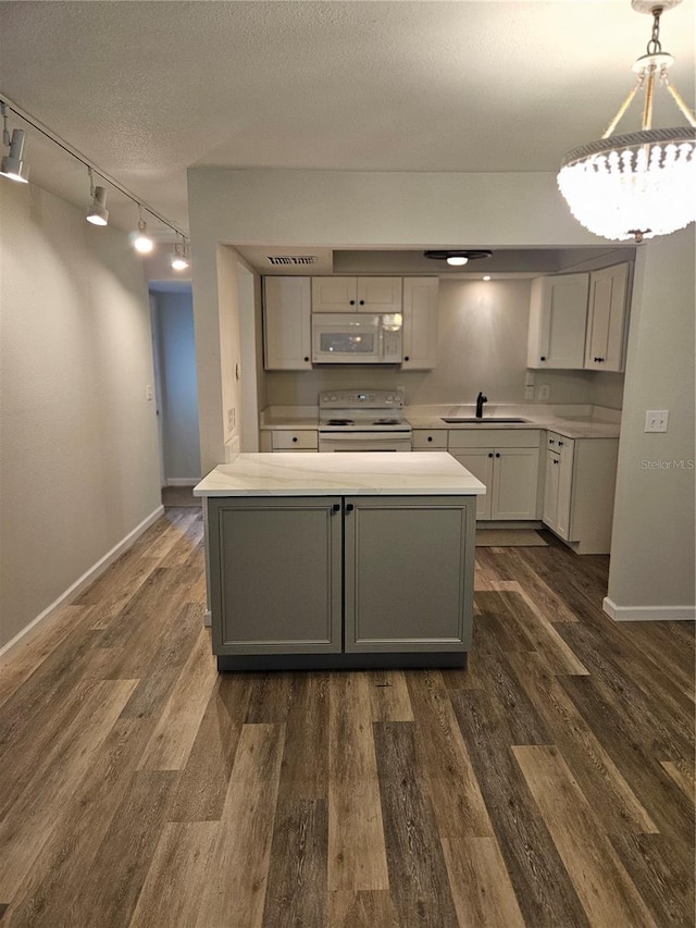 414 Danube Ave, Tampa, FL 33606 - kitchen with a sink, white appliances, track lighting, dark wood-style flooring, and light countertops