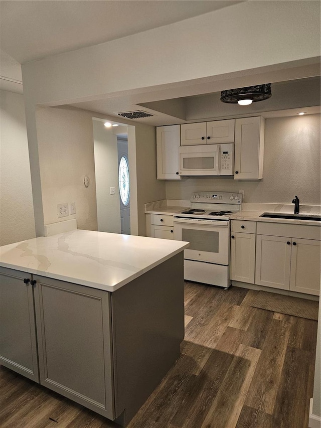 414 Danube Ave, Tampa, FL 33606 - kitchen with white appliances, dark wood finished floors, a sink, a peninsula, and white cabinets