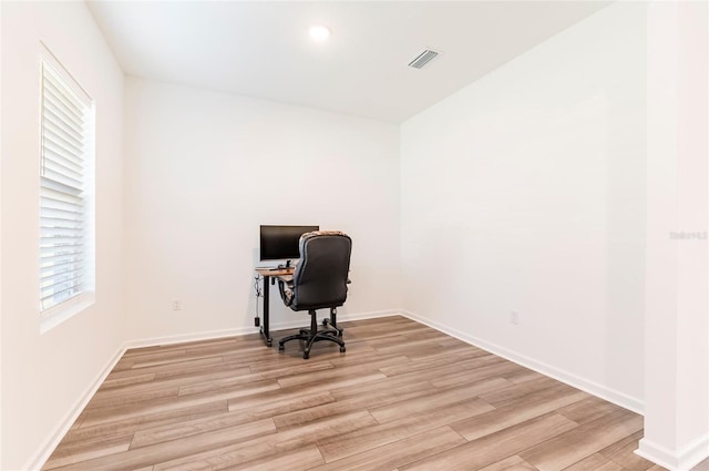 office area with baseboards, light wood-style flooring, and visible vents