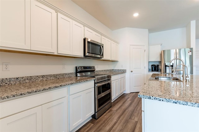 kitchen featuring a sink, stainless steel appliances, white cabinetry, dark wood-style flooring, and light stone countertops
