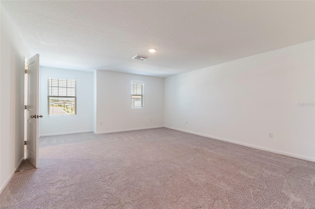 unfurnished room featuring baseboards, visible vents, and light colored carpet