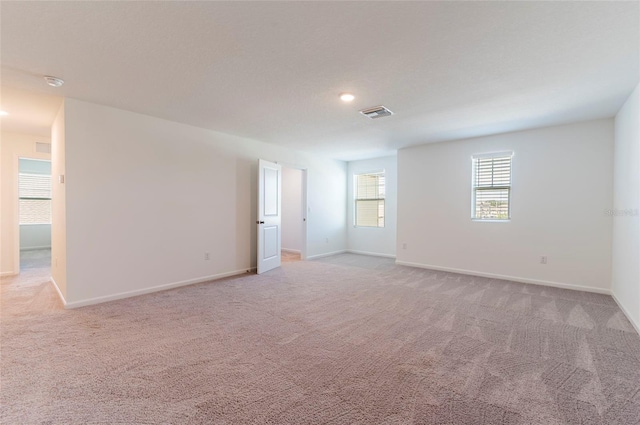 empty room featuring baseboards, visible vents, and light colored carpet