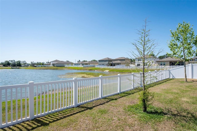 view of yard with a fenced backyard, a residential view, and a water view