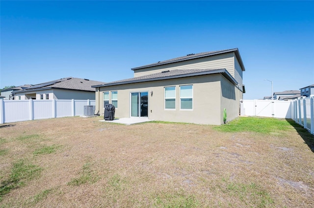back of property featuring a gate, central AC, a fenced backyard, a yard, and stucco siding