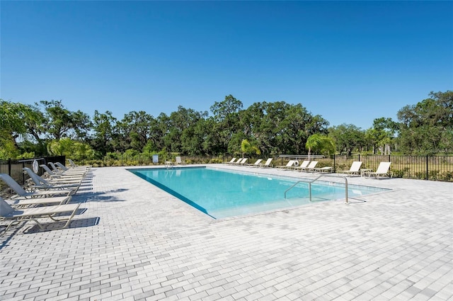 community pool with fence and a patio area