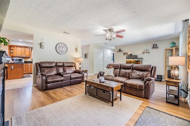 6821 Mary Lou Ln, Wesley Chapel, FL 33544 - living room with light wood-style floors, a ceiling fan, a textured ceiling, and visible vents