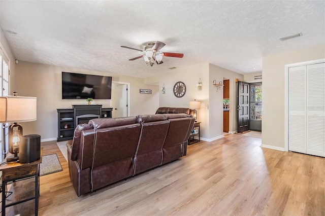 6821 Mary Lou Ln, Wesley Chapel, FL 33544 - living room with a ceiling fan, a textured ceiling, visible vents, baseboards, and light wood-style flooring