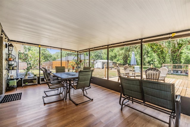 6821 Mary Lou Ln, Wesley Chapel, FL 33544 - sunroom with expansive windows, a wooden deck, outdoor dining area, and wood finished floors