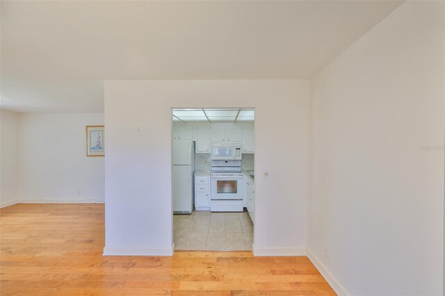 1802 Bedford Ter Unit 187, Sun City Center, FL 33573 - kitchen featuring white appliances, light wood-type flooring, and baseboards