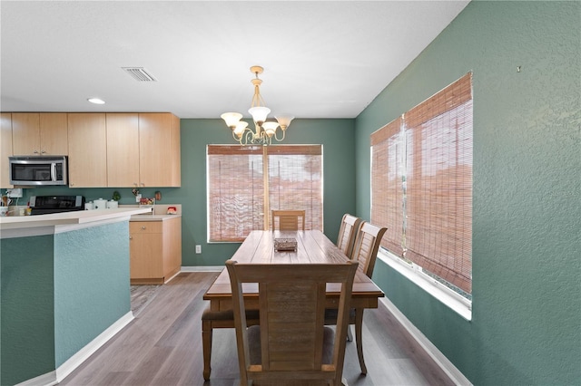 11449 Crestlake Village Dr, Riverview, FL 33569 - dining room with a textured wall, visible vents, light wood finished floors, and an inviting chandelier
