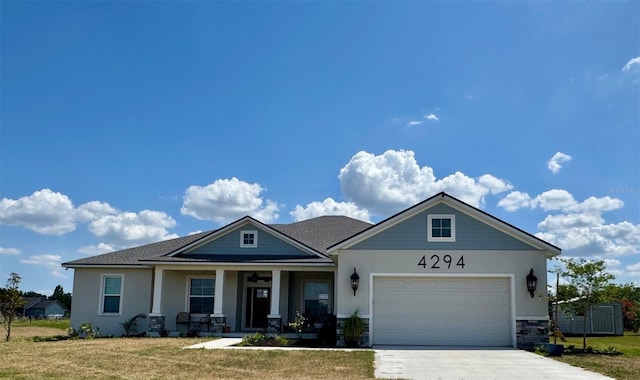 view of front facade featuring covered porch, an attached garage, driveway, and a front yard