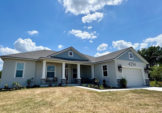 view of front of home with covered porch, concrete driveway, a front lawn, and a garage