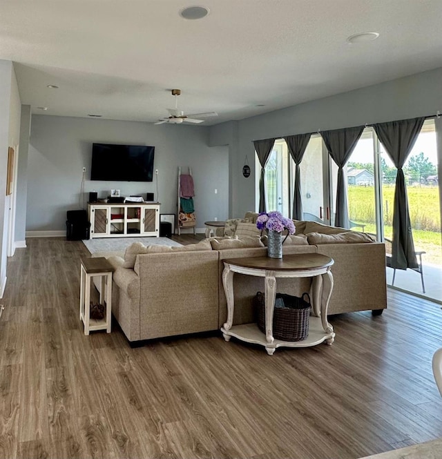 living room featuring baseboards, a ceiling fan, and wood finished floors