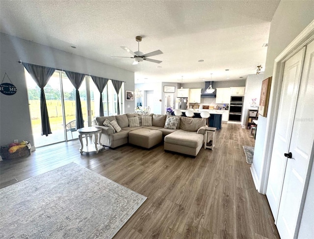 living area featuring a ceiling fan, a textured ceiling, and dark wood finished floors