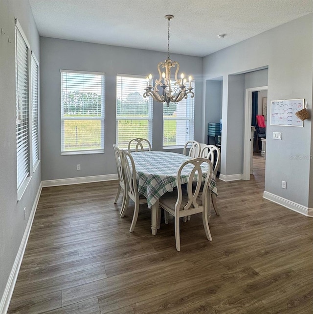 dining space with a healthy amount of sunlight, dark wood-type flooring, and a chandelier
