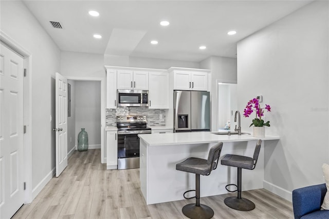 13117 4th St E, Madeira Beach, FL 33708 - kitchen with appliances with stainless steel finishes, a sink, a breakfast bar, a peninsula, and decorative backsplash