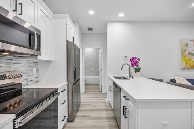 13117 4th St E, Madeira Beach, FL 33708 - kitchen featuring stainless steel appliances, a sink, light wood-style floors, white cabinets, and recessed lighting