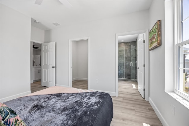 13117 4th St E, Madeira Beach, FL 33708 - bedroom featuring light wood-style flooring, baseboards, ensuite bath, and a walk in closet