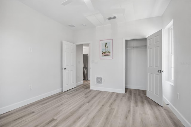 13117 4th St E, Madeira Beach, FL 33708 - unfurnished bedroom with light wood-style flooring, a closet, baseboards, and freestanding refrigerator