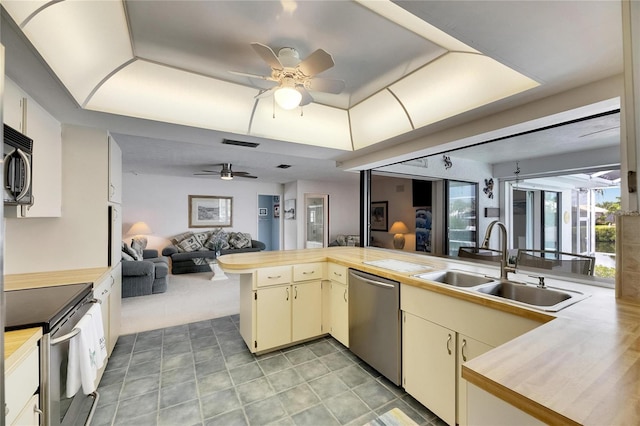 927 Golf Island Dr, Apollo Beach, FL 33572 - kitchen with stainless steel appliances, a sink, a ceiling fan, open floor plan, and cream cabinetry