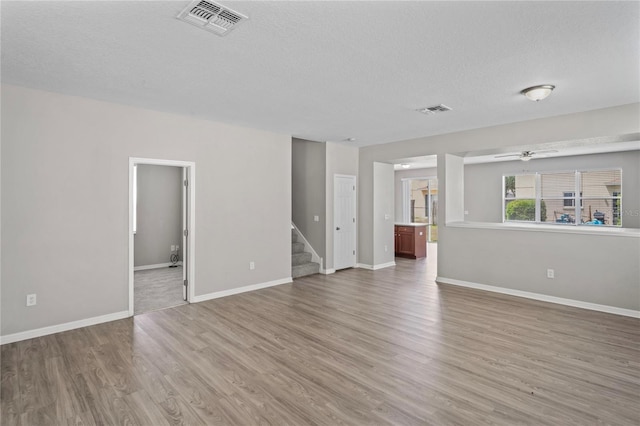 18837 Litzau Ln, Land O Lakes, FL 34638 - unfurnished living room featuring a ceiling fan, stairs, wood finished floors, a textured ceiling, and baseboards
