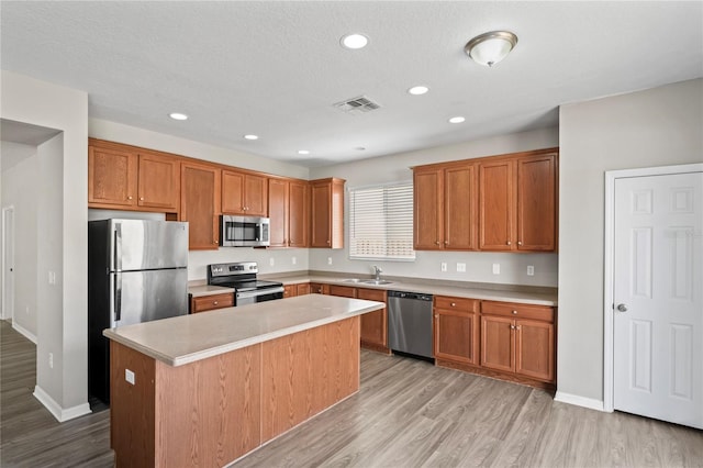 18837 Litzau Ln, Land O Lakes, FL 34638 - kitchen with appliances with stainless steel finishes, a center island, light wood-style flooring, light countertops, and recessed lighting