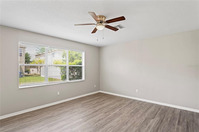 18837 Litzau Ln, Land O Lakes, FL 34638 - empty room with wood finished floors, a ceiling fan, baseboards, and a textured ceiling