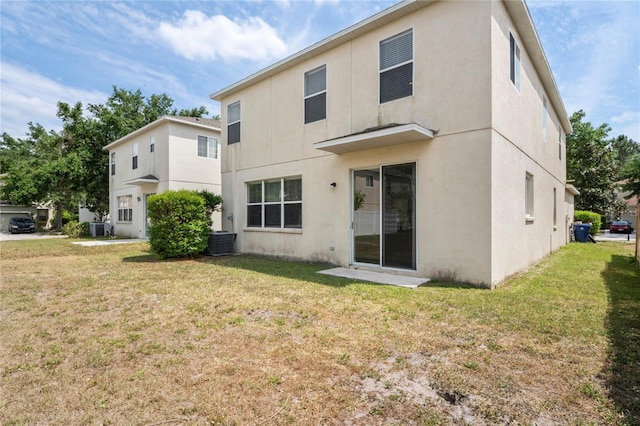 18837 Litzau Ln, Land O Lakes, FL 34638 - back of property with stucco siding, a lawn, and central AC