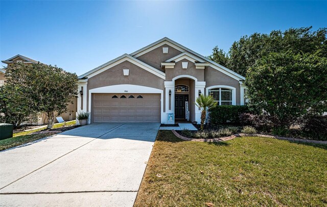 traditional home with stucco siding, an attached garage, driveway, and a front yard