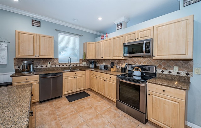 kitchen featuring light brown cabinetry, stainless steel appliances, a sink, and backsplash
