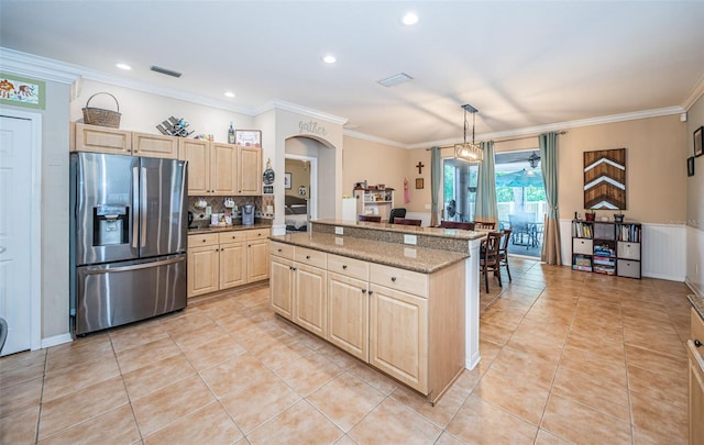 kitchen featuring crown molding, light tile patterned flooring, stainless steel fridge, light brown cabinets, and a kitchen island