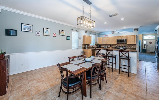 dining space featuring visible vents, ornamental molding, light tile patterned floors, and a wainscoted wall