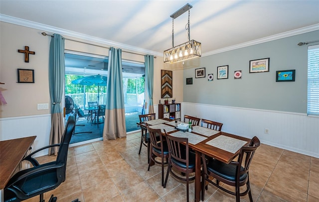 dining area featuring a healthy amount of sunlight, a wainscoted wall, ornamental molding, and light tile patterned flooring
