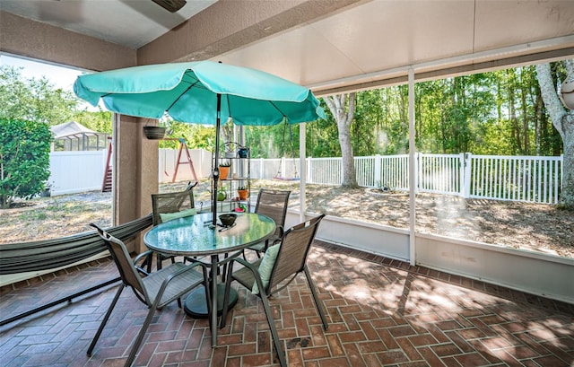 sunroom / solarium with a ceiling fan and outdoor dining space