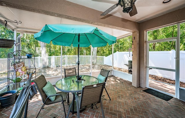 sunroom / solarium with plenty of natural light, outdoor dining space, and ceiling fan