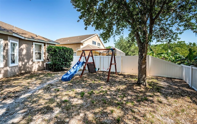 view of yard with central AC unit, a fenced backyard, and a playground